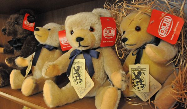 Teddybären mit dem Wappen der Stadt Sonneberg auf dem Etikett sitzen auf einem Regal.